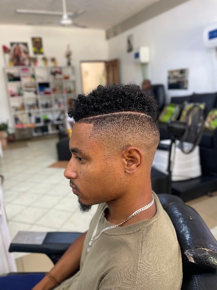 Black client receiving barber grooming in a barbershop